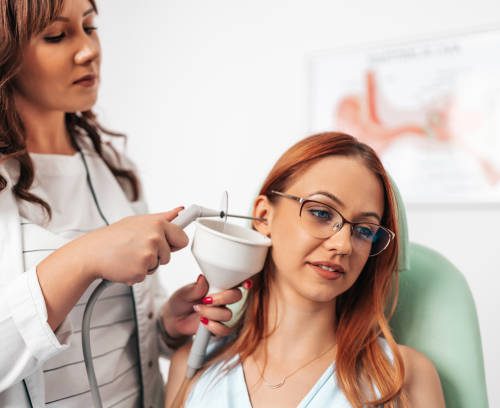 Earwax microsuction by Waxedears II Otolaryngologist doing ear irrigation and earwax removal to a young adult woman with modern medical equipment. Healthcare and medicine concept.