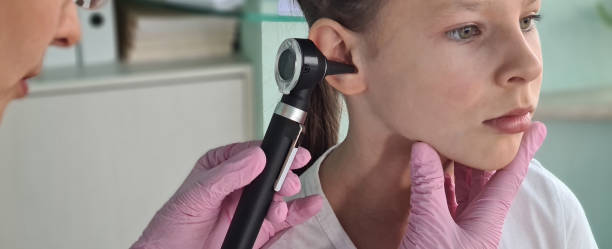 Waxed Ears child service Otorhinolaryngologist examines little girl ear with otoscope. Adenoiditis as cause of otitis media in children