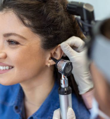 Close up of a female doctor carefully holding the ear of his patient to establish a clearer view of the inside of his ear, to see if he requires hearing aids at a modern clinic